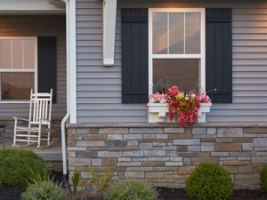 Big house with beautiful window, pale gray siding, and stone accents