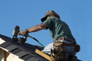 A roofer on a roof putting down shingles