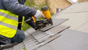 Roofer nailing shingles to a roof deck